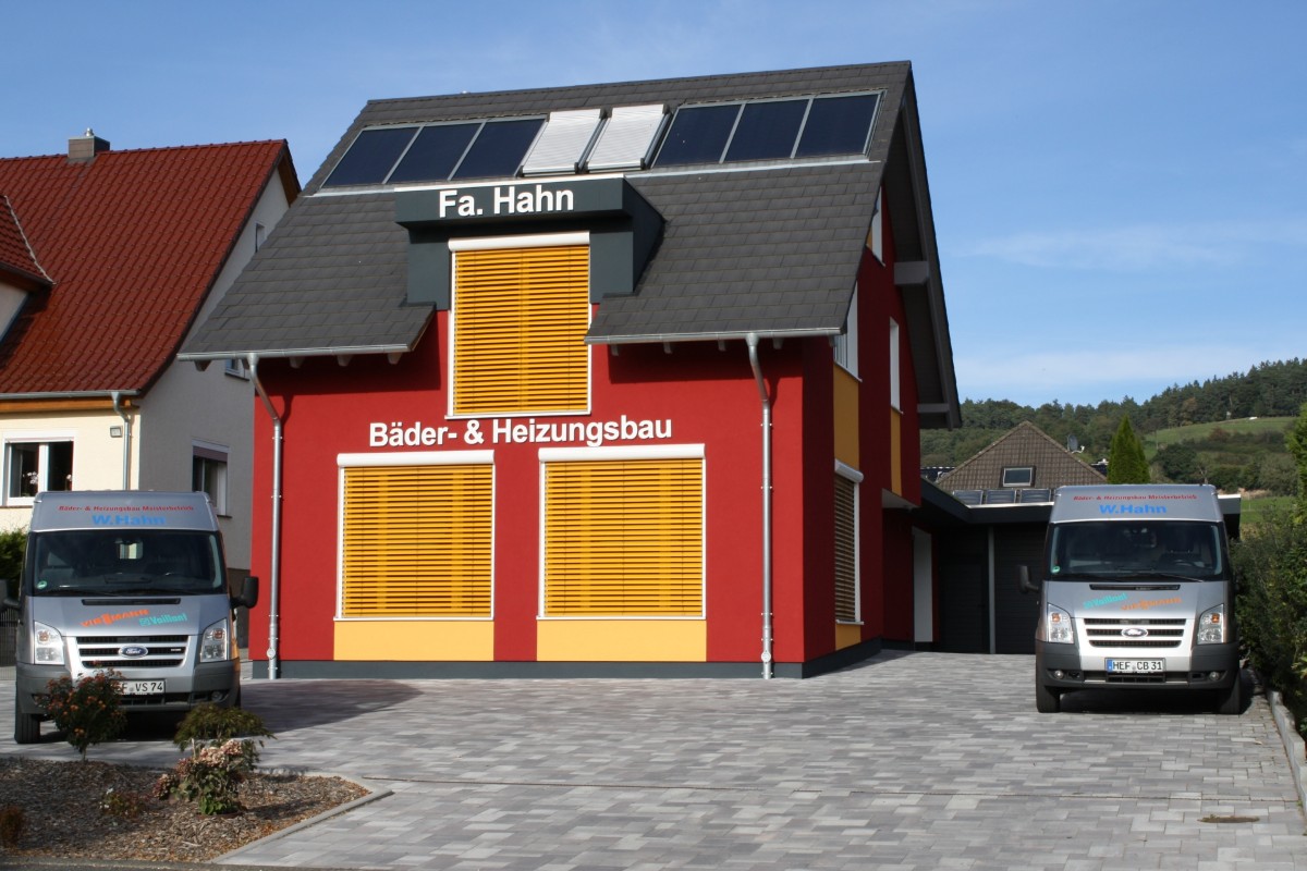 Firmengebäude von Bäder & Heizungsbau Hahn in Alheim-Heinebach mit Solaranlage und Firmenfahrzeugen